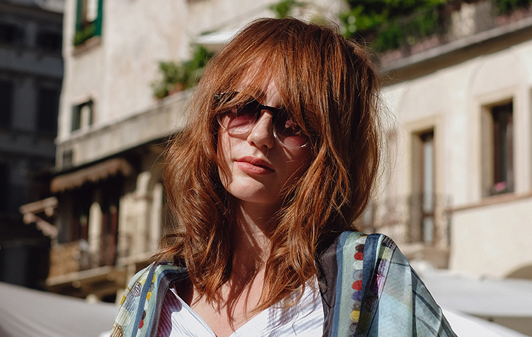 Girl with red, wavy hair and curtain bangs