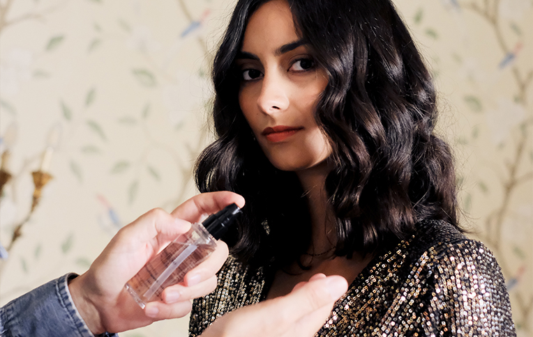 Brunette girl with long, wavy hair getting hair oil applied.