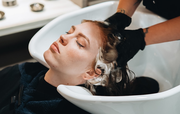 Immagine di una ragazza mentre le stanno lavando i capelli in una postazione da lavaggio ad un salone Rossano Ferretti Parma