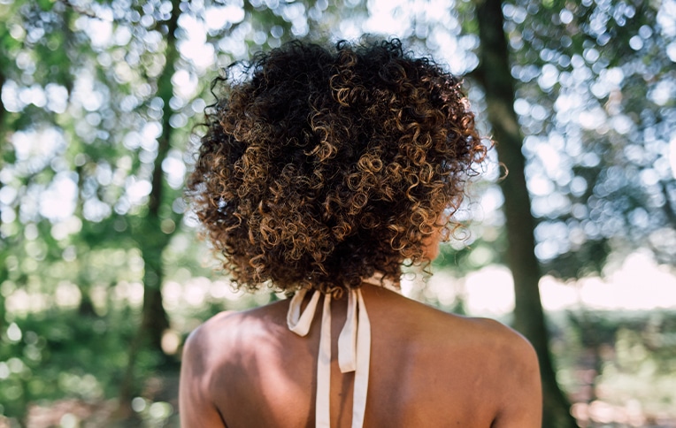 Immagine di una ragazza di spalle con capelli castani e molto ricci