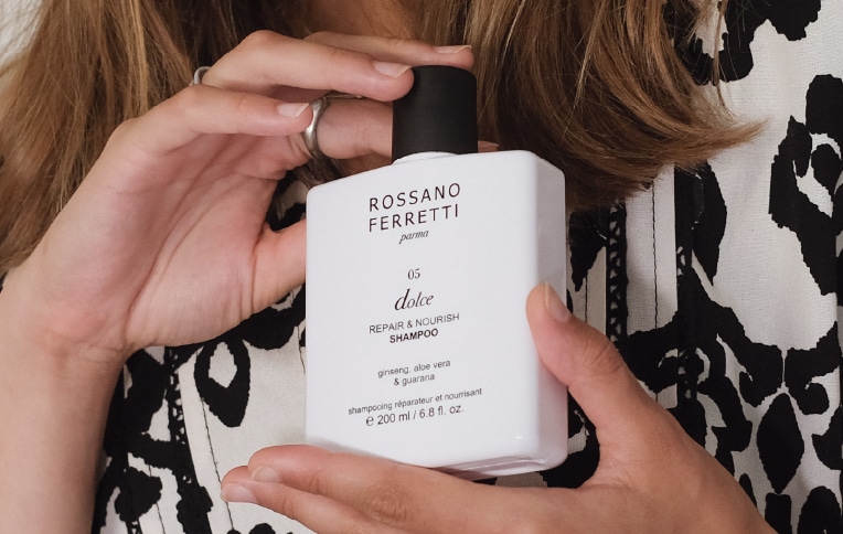 Image of a model displaying Rossano Ferretti Parma's Dolce repair & nourish shampoo in her hands.