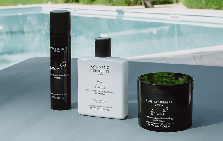Image of the shampoo, mask, and smoothing serum from the Intenso line by Rossano Ferretti Parma, with a pool background.