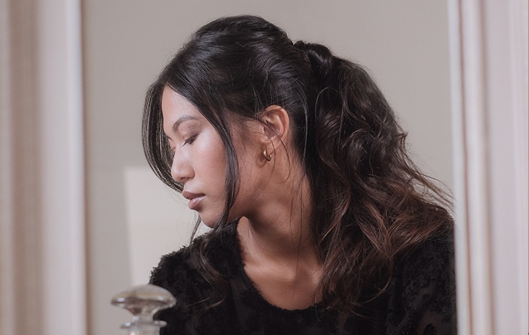 Image of a girl with dark, wavy hair in a ponytail looking sideways.