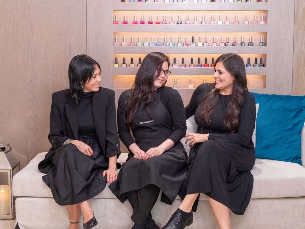 Image of three women sitting and smiling at each other.