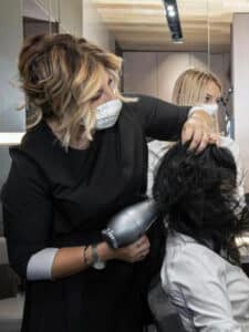 Image of a hairdresser blow-drying a client's hair.