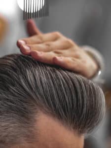 A man's hairstyle as he brushes through his hair.
