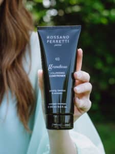 Image of a model showing Rossano Ferretti Parma's Grandioso volumizing conditioner in her hands. 