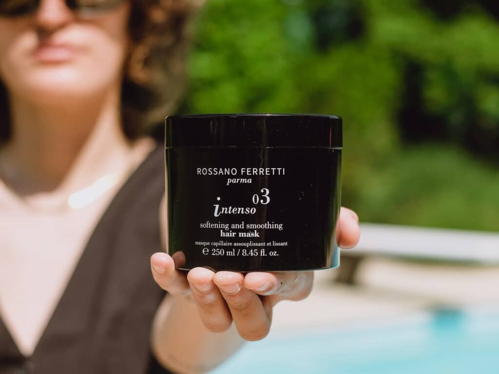 Image of a girl showing the Intenso smoothing mask by Rossano Ferretti Parma in her hands. 