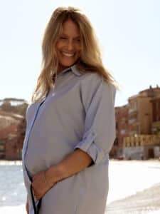 Image of a pregnant woman with blonde, wavy hair smiling.