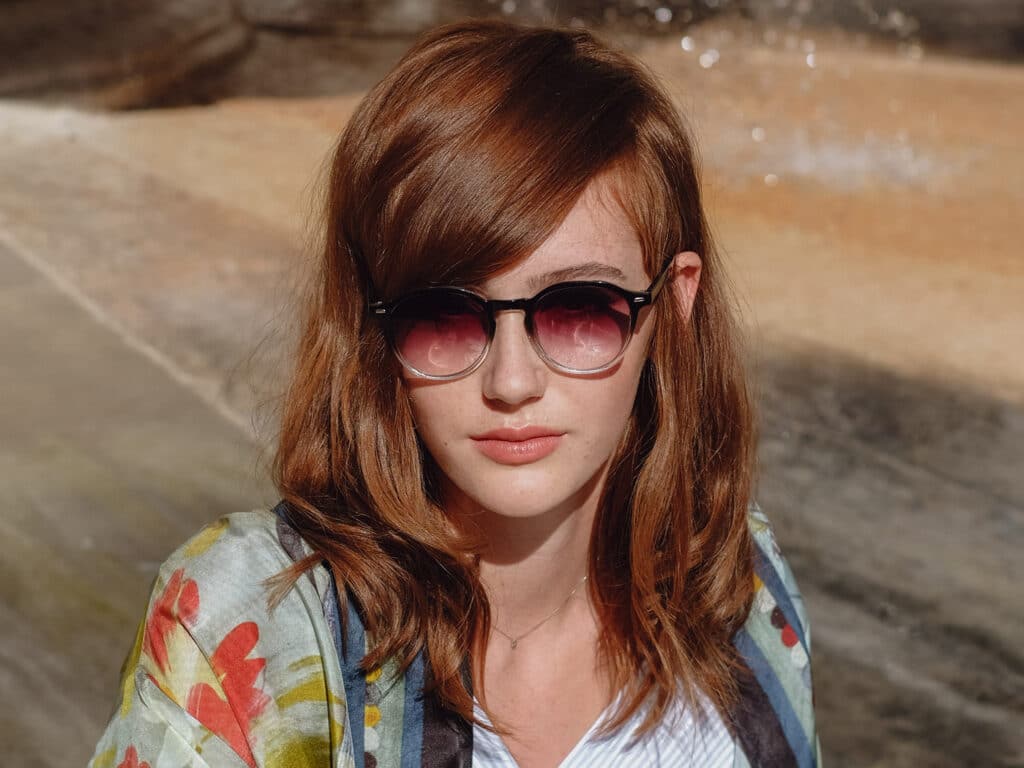 Image of a girl with red, wavy hair wearing sunglasses