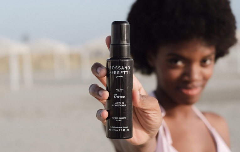 Girl holding Rossano Ferretti Parma's Vivace leave-in conditioner. 