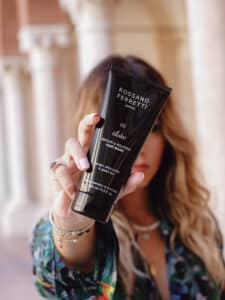 Image of a girl with blonde, wavy hair holding the Dolce nourishing mask by Rossano Ferretti Parma in her hand