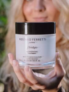 Image of a girl with blonde, wavy hair holding the Prodigio regenerating treatment by Rossano Ferretti Parma in her hand.