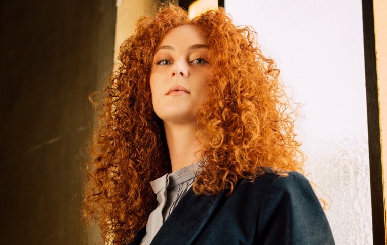 Image of a redhead girl with long, very curly, and voluminous hair.