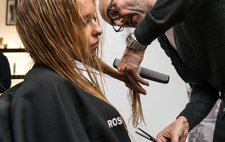 Immagine di Rossano Ferretti che taglia i capelli di una modella bionda.