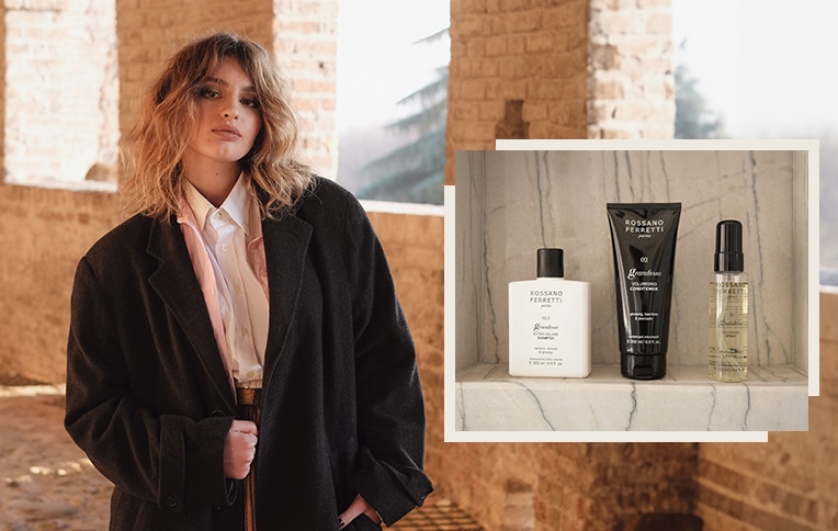 Image of a girl with short blonde hair with the products from the Grandioso line by Rossano Ferretti Parma. Shampoo, conditioner, and Grandioso volumizing spray