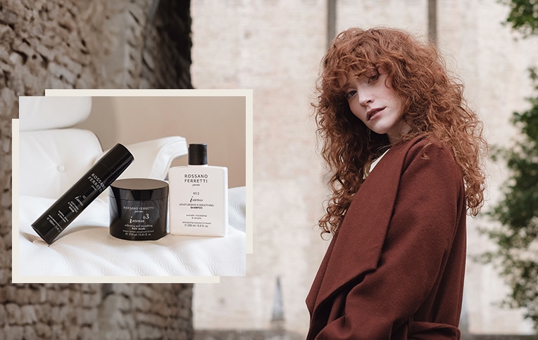 Image of a girl with long, curly red hair with the products from the Intenso line by Rossano Ferretti Parma. Shampoo, mask, and Intenso smoothing serum.