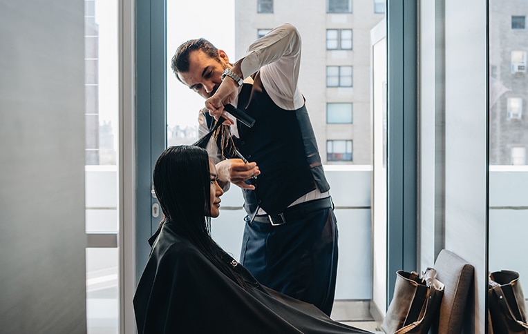Immagine di un parrucchiere mentre taglia i capelli a una cliente.