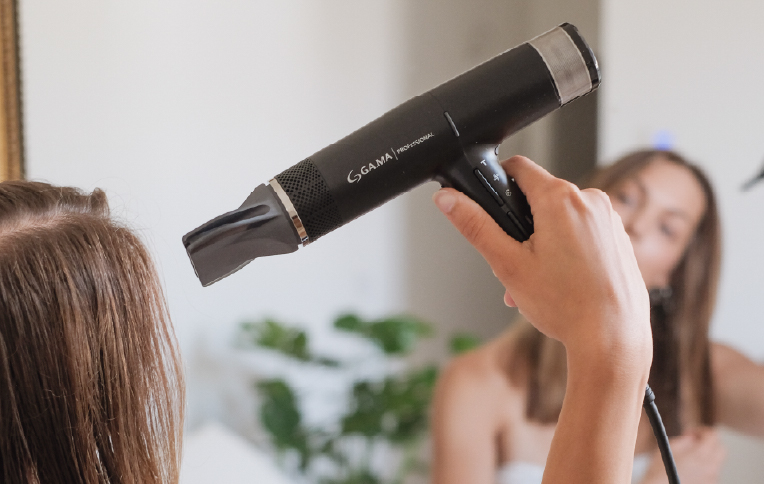 Girl drying her hair with a Gama hairdryer.