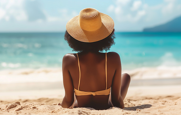 Girl wearing a straw hat lying on the beach sunbathing