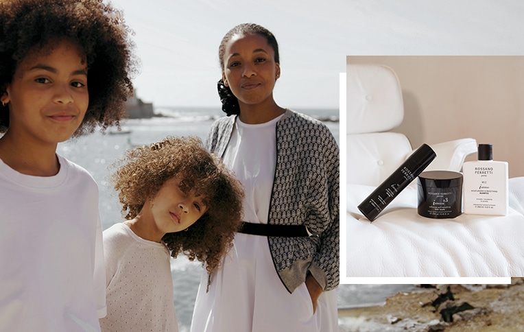 Image of a woman and two children with short, curly, voluminous hair smiling against a backdrop of the sea, alongside an image of Rossano Ferretti Parma products from the Intenso smoothing routine with the moisturising & smoothing shampoo, the softening & smoothing mask and the softening & smoothing serum.