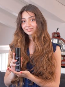 Image of a girl with long, brown, wavy hair holding the Favoloso movement spray by Rossano Ferretti Parma.