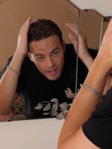 Man adjusting his hair in front of a mirror.